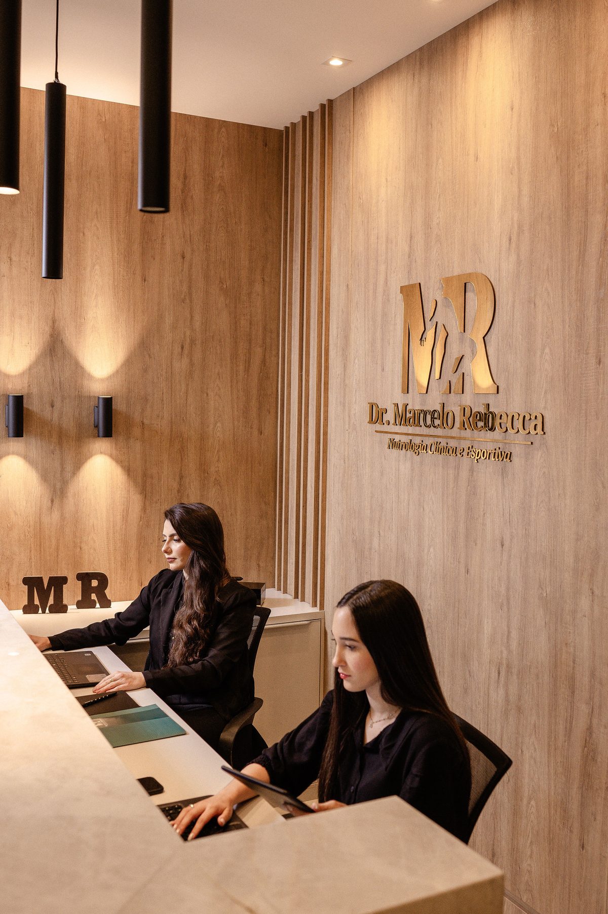 Recepção do Instituto Dr. Marcelo Rebecca, com painel de madeira e logotipo dourado