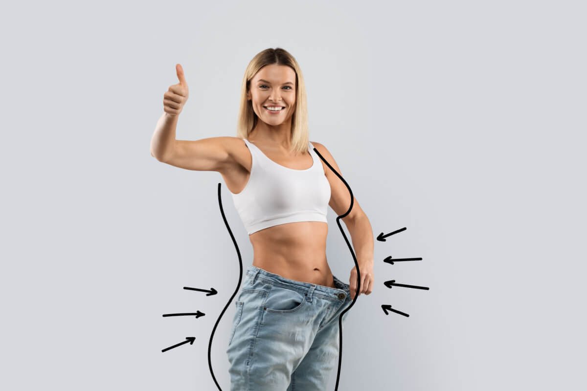 Mulher sorrindo de calça jeans larga, representando a perda de peso